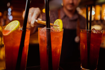 Pink and red Fresh colorful exotic alcoholic cocktail with lemon and ice in the bar. Colorful pink Soft drink with ice on the bar desk. Red colorful Mojito