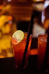 Pink and red Fresh colorful exotic alcoholic cocktail with lemon and ice in the bar. Colorful pink Soft drink with ice on the bar desk. Red colorful Mojito