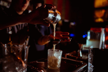 barman adding ingredients and creating cocktail drinks on bar counter