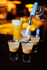 Bartender man making hot alcohol shots on the bar in the pub with a professional burner. The bartender lights a lighter over a glass.Relax in the nightclub. Hot fire drinks. Lets the party