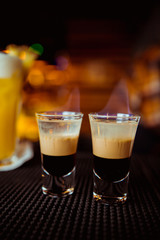Bartender man making hot alcohol shots on the bar in the pub with a professional burner. The bartender lights a lighter over a glass.Relax in the nightclub. Hot fire drinks. Lets the party