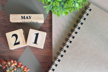 May 21. Date of May month. Number Cube with a flower and notebook on Diamond wood table for the background.
