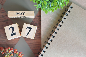 May 27. Date of May month. Number Cube with a flower and notebook on Diamond wood table for the background.