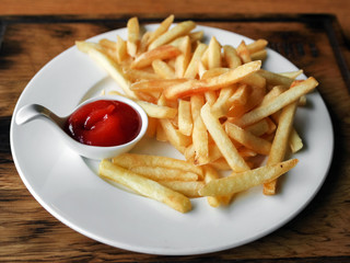 French fries on a plate with a portion of ketchup. Close-up of natural light