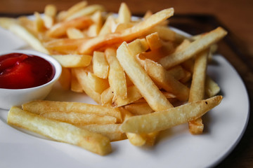 Serving of french fries on a plate, fragment. Natural light