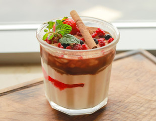 A multilayer tender dessert decorated with a cinnamon stick, slices of berries and mint leaves...