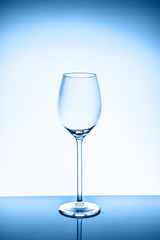 Wineglass on the light background. Fine cristal glassware concept. Vertical, toned in blue
