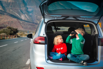 little boy and girl looking through binoculars, family travel by car in mountains
