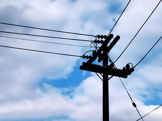 Silhouettes high-voltage wires on a pole. On the blue sky background and copy space.