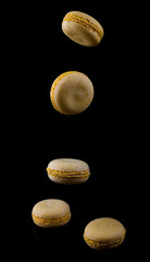 yellow macaroons fall down on a black background