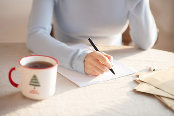 Woman in grey sweater sitting at the table and making notes