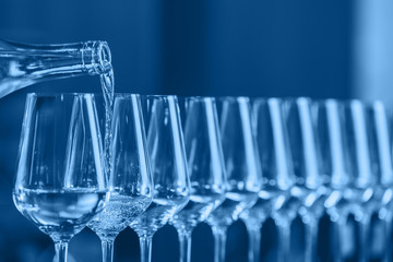 Wine glasses in a row. Pouring wine. Buffet table celebration of wine tasting. Nightlife, celebration and entertainment concept. Horizontal, cold toned image