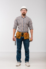 Young technician with toolbelt on his waist standing in front of camera