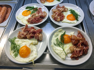 Fried eggs with bacon and a sprig of dill on a white plate, ready to serve.