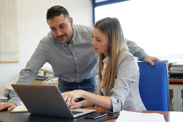 Co-workers in office working on laptop computer