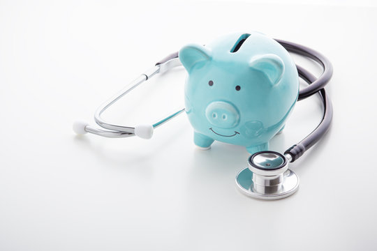 Piggy bank with stethoscope on white table