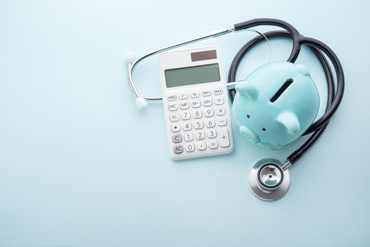 Piggy bank with stethoscope and calculator on blue background