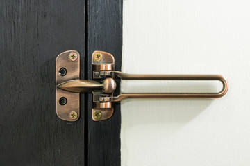Safety latch guard on hotel room door, on black door and white wall,  Locked doors in hotel.