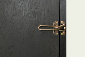Safety latch guard on hotel room door, on black door and white wall,  Locked doors in hotel.