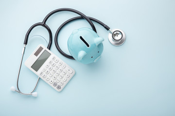 Piggy bank with stethoscope and calculator on blue background