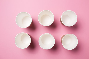 Paper cup for hot coffee or tea on a pink isolated background.