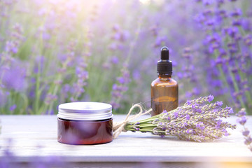 Essential lavender oil in the bottle with dropper on the gray wooden desk. Horizontal close-up. Skin care cream.