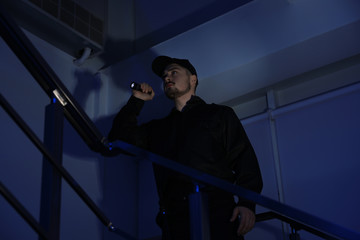 Fototapeta na wymiar Male security guard with flashlight on stairs in darkness