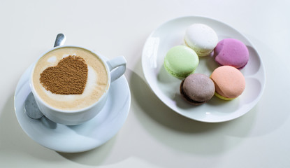Delicious macaroons and cappuccino on a large bright table in a cozy coffee shop
