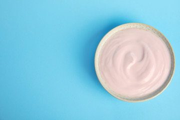 Tasty organic yogurt on light blue background, top view. Space for text