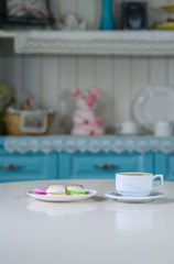 Delicious macaroons and cappuccino on a large bright table in a cozy coffee shop