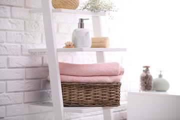 Fototapeta na wymiar Basket with clean towels on shelving unit in bathroom
