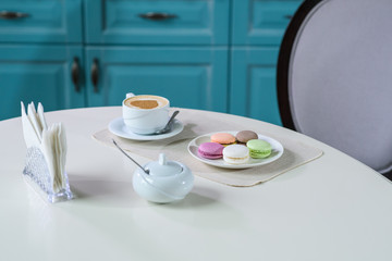 Delicious cappuccino and macaroons prepared on a table for a guest