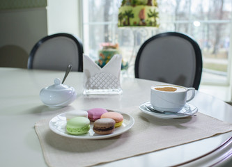 Delicious cappuccino and macaroons prepared on a table for a guest