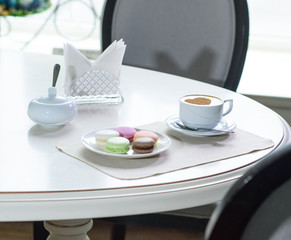 Delicious cappuccino and macaroons prepared on a table for a guest