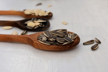 Closeup Sunflower seeds and pumpkin seeds in a wooden spoon at light wooden background/ Closeup still life food photography