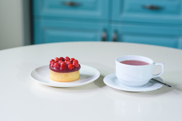 Delicious berry tea and tarte with raspberries on a table in a cozy coffee shop