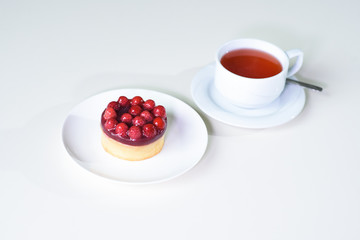 Delicious berry tea and tarte with raspberries on a table in a cozy coffee shop