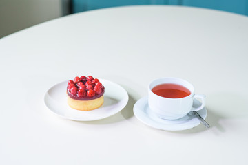 Delicious berry tea and tarte with raspberries on a table in a cozy coffee shop