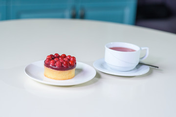 Delicious berry tea and tarte with raspberries on a table in a cozy coffee shop