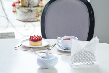 Delicious berry tea and tarte with raspberries prepared on a table for a guest in a cozy cafe