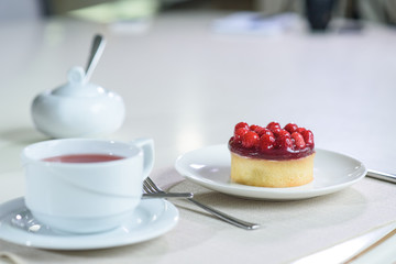 Delicious berry tea and tarte with raspberries prepared on a table for a guest in a cozy cafe