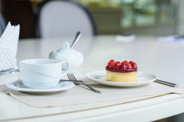 Delicious berry tea and tarte with raspberries prepared on a table for a guest in a cozy cafe