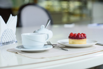 Delicious berry tea and tarte with raspberries prepared on a table for a guest in a cozy cafe