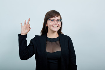 Young beautiful caucasian woman showing ok sign gesture wearing black clothes on isolated gray background