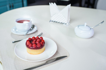 Delicious berry tea and tarte with raspberries prepared on a table for a guest in a cozy cafe