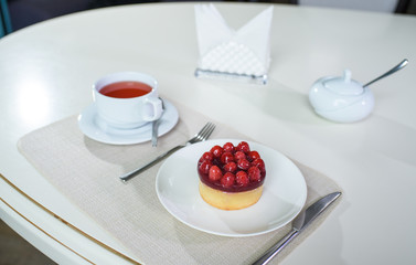 Delicious berry tea and tarte with raspberries prepared on a table for a guest in a cozy cafe