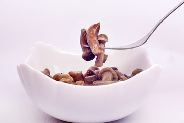 small pickled mushrooms impaled on fork, eat edible mushrooms agaric honey.