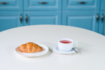 Fruit tea and delicious fresh croissant on the table in a cozy coffee shop