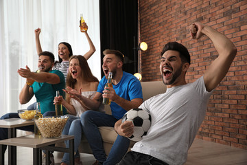 Group of friends watching football at home