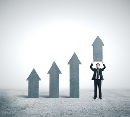 Businessman holding concrete arrow.